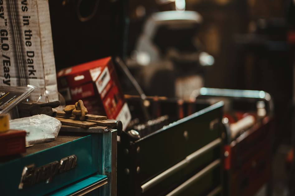 Close-up of a sleek black rolling tool chest with drawers open showing organized wrenches and sockets