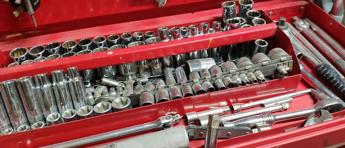 extreme tools rolling tool box with open drawers showing organized sockets, wrenches, and power tools on a garage floor