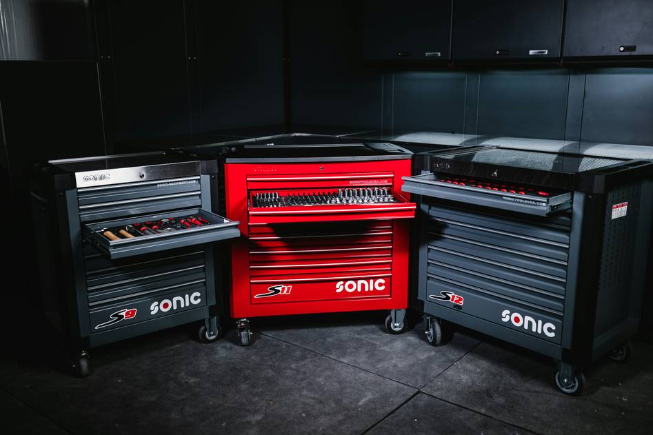 Two mechanics smiling beside a row of high-quality rolling tool chests in a clean workshop